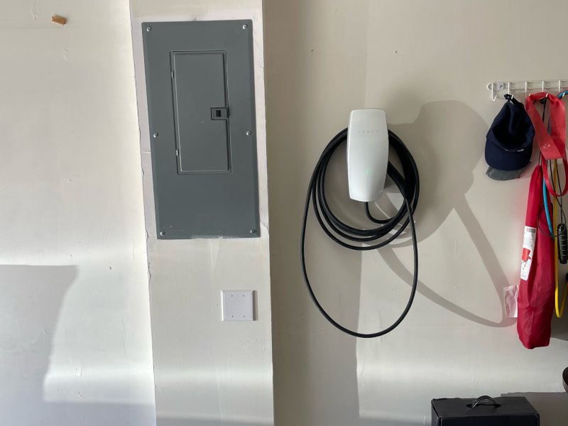 EV Charger hanging on the wall next to the gray electrical box and other items