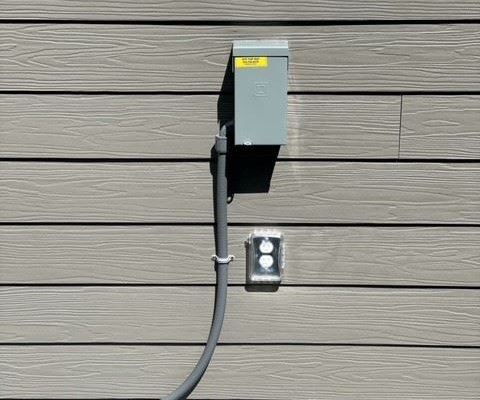 gray hot tub electrical control box on the siding of beige home